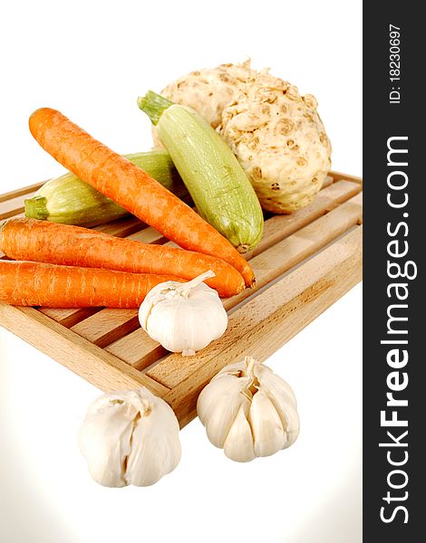 Mix of vegetables on a wooden plate on a white background. Mix of vegetables on a wooden plate on a white background