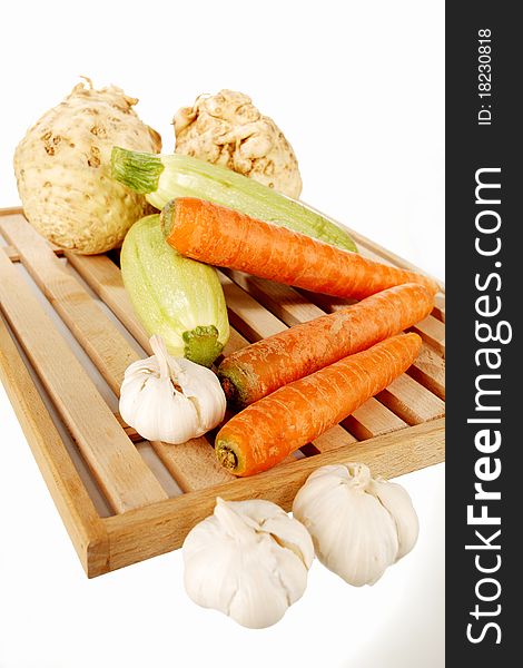 Vegetables on a wooden plate on a white background