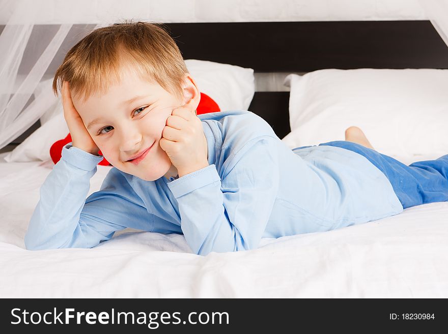 A white-headed glad boy lies on a bed in a comfortable situation. A white-headed glad boy lies on a bed in a comfortable situation