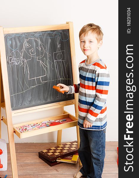 A white-headed glad boy draws a chalk on a board