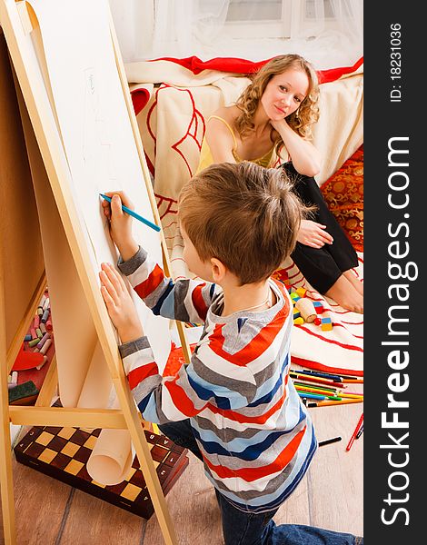 Mother with a son play and draw crayons on the white sheet of paper