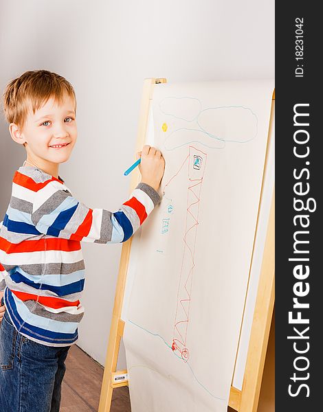 A boy draws crayons on the white sheet of paper