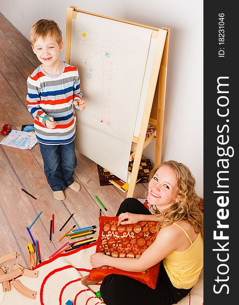 Mother with a son play and draw crayons on the white sheet of paper