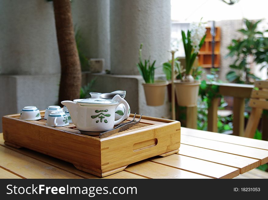 Tea set on a small wooden table，with narcissus behind it。