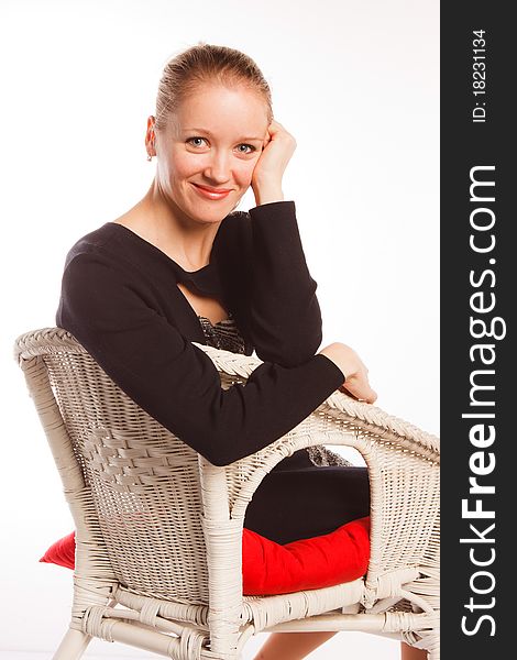 A charming beautiful  woman sits in an arm-chair on a white background