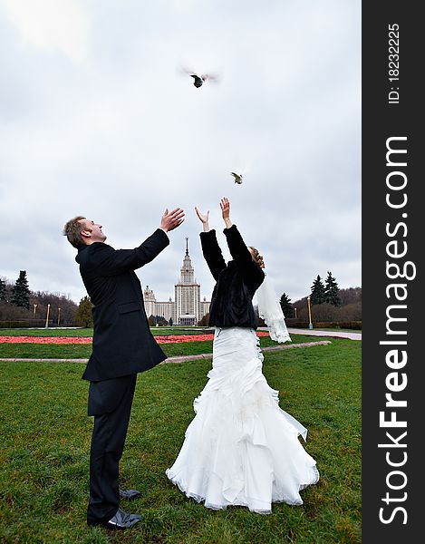 Happy bride and groom issue from the hands of pigeons on wedding walk. Happy bride and groom issue from the hands of pigeons on wedding walk