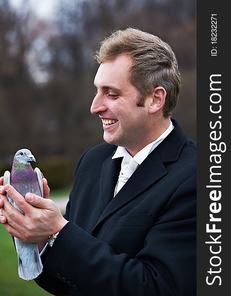 Joyful groom with pigeons on hands on wedding walk