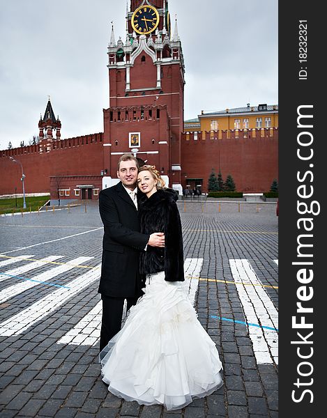 Happy bride and groom on Red Square near the Kremlin's Spassky Tower in Moscow. Happy bride and groom on Red Square near the Kremlin's Spassky Tower in Moscow