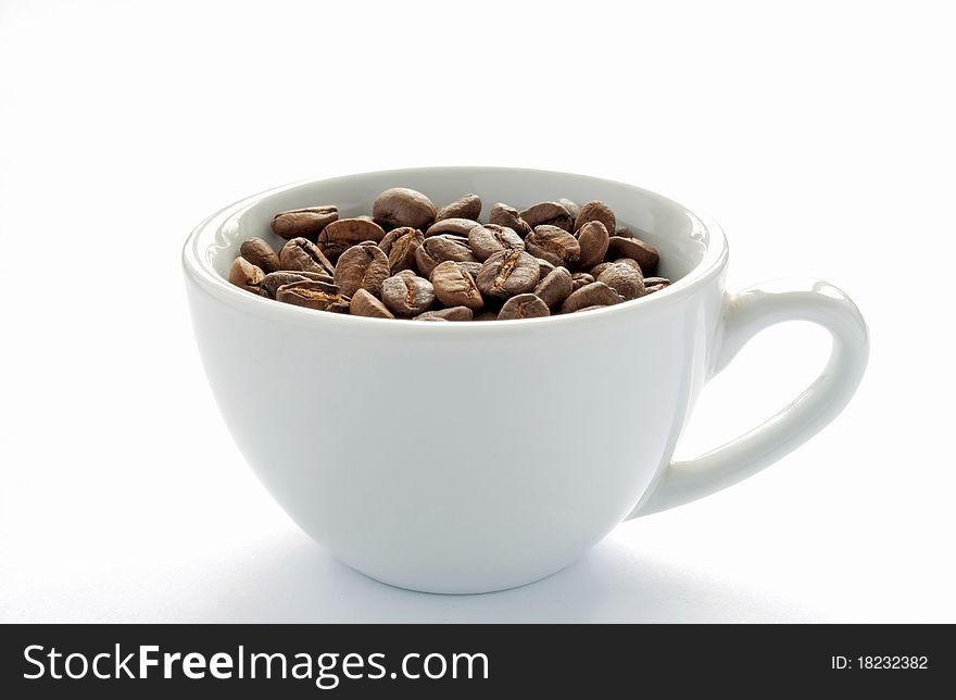 Brown roasted coffee beans in a white cup