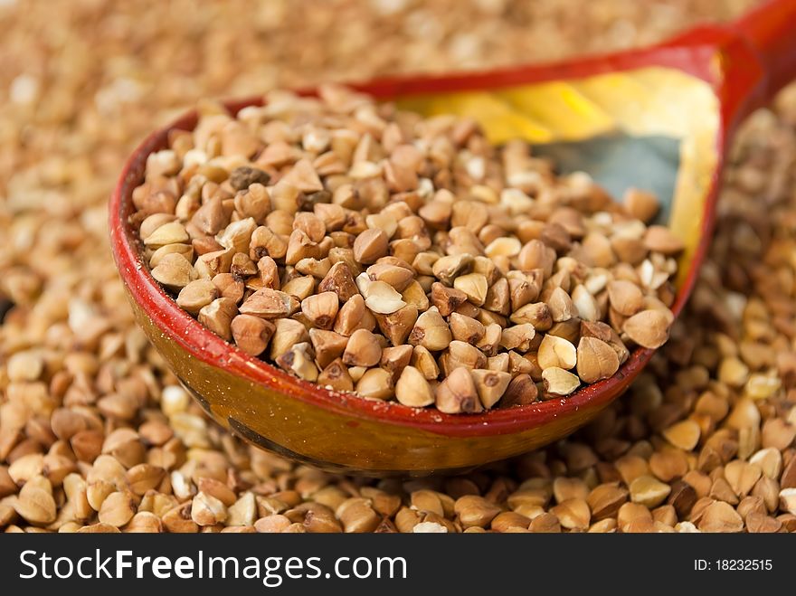 Buckwheat in hohloma spoon over buckwheat background