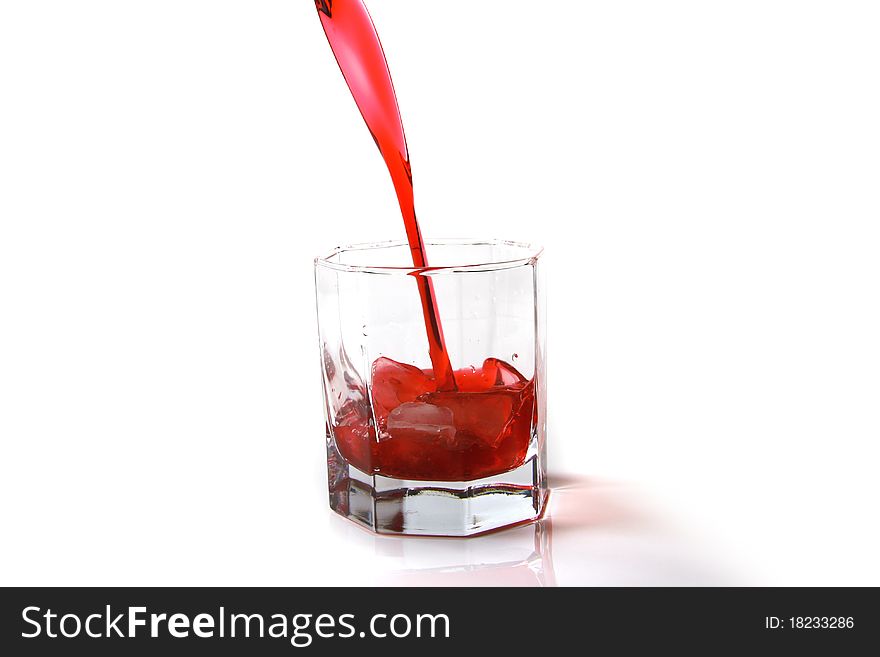 Red cocktail being poured into a glass on white background