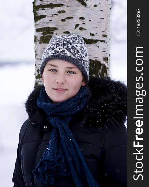 Young beautiful girl in hat and scarf leaning the tree. Young beautiful girl in hat and scarf leaning the tree