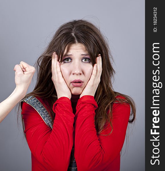 Sad girl in red and hand fist. Studio shot.