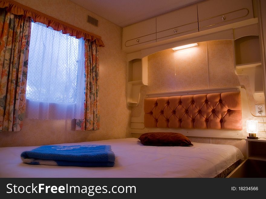 A scene inside of a comfortable, romantic bedroom with nightstands and lamps in luxury mobile home or motor home. A scene inside of a comfortable, romantic bedroom with nightstands and lamps in luxury mobile home or motor home.