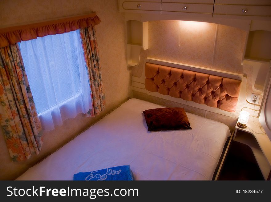 A scene inside of a comfortable, romantic bedroom with nightstands and lamps in luxury mobile home or motor home. A scene inside of a comfortable, romantic bedroom with nightstands and lamps in luxury mobile home or motor home.