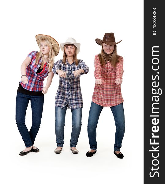 Three girls in hats imitate horse riding on a white background