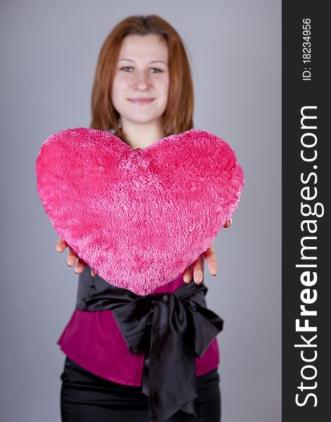 Red-haired girl with heart toy. Studio shot.
