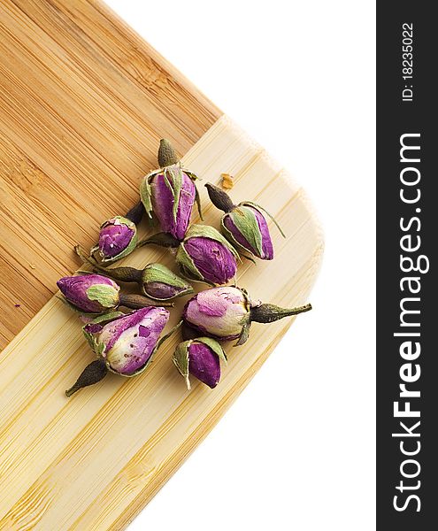 Dried tea roses on a bamboo cutting board