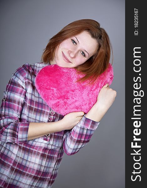Red-haired girl with heart toy. Studio shot.