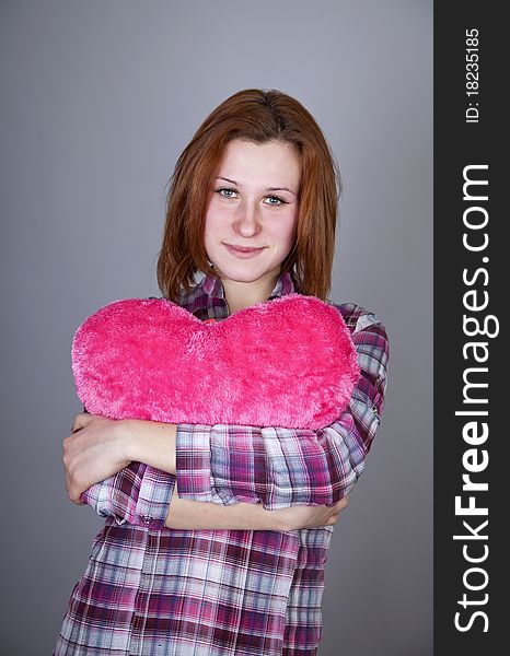 Red-haired girl with heart toy. Studio shot.