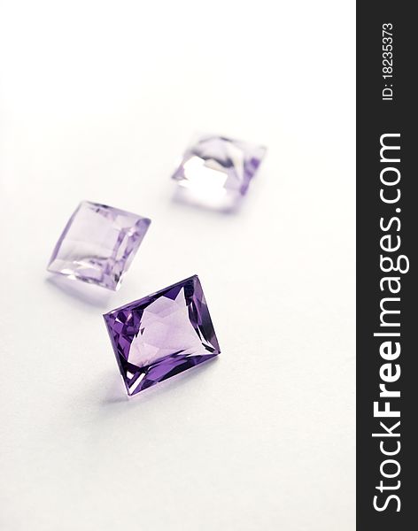 A close-up image of three princess-cut amethysts on a white back ground