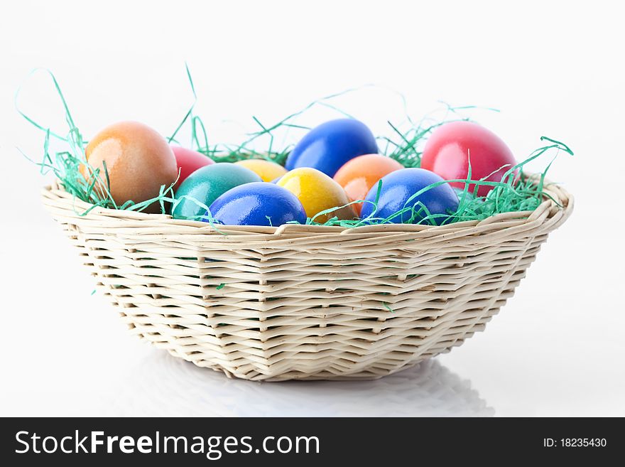 Colored easter eggs in a basket on white background