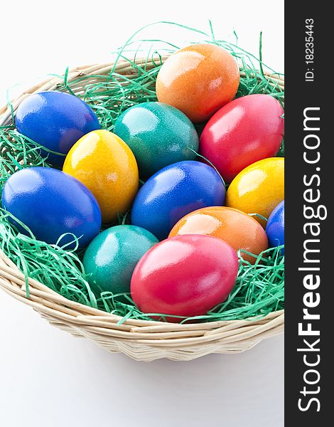 Colored easter eggs in a basket on white background