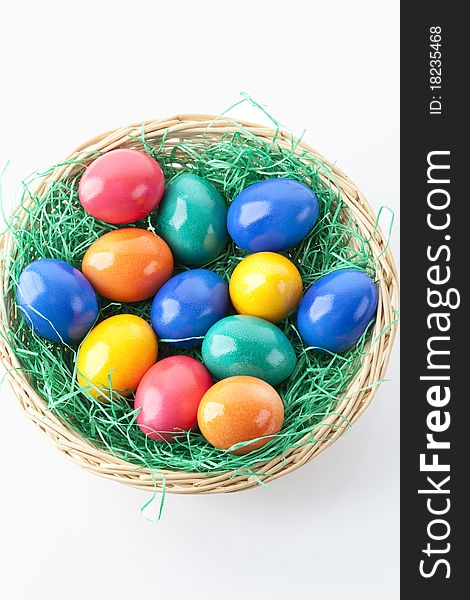 Colored easter eggs in a basket on white background