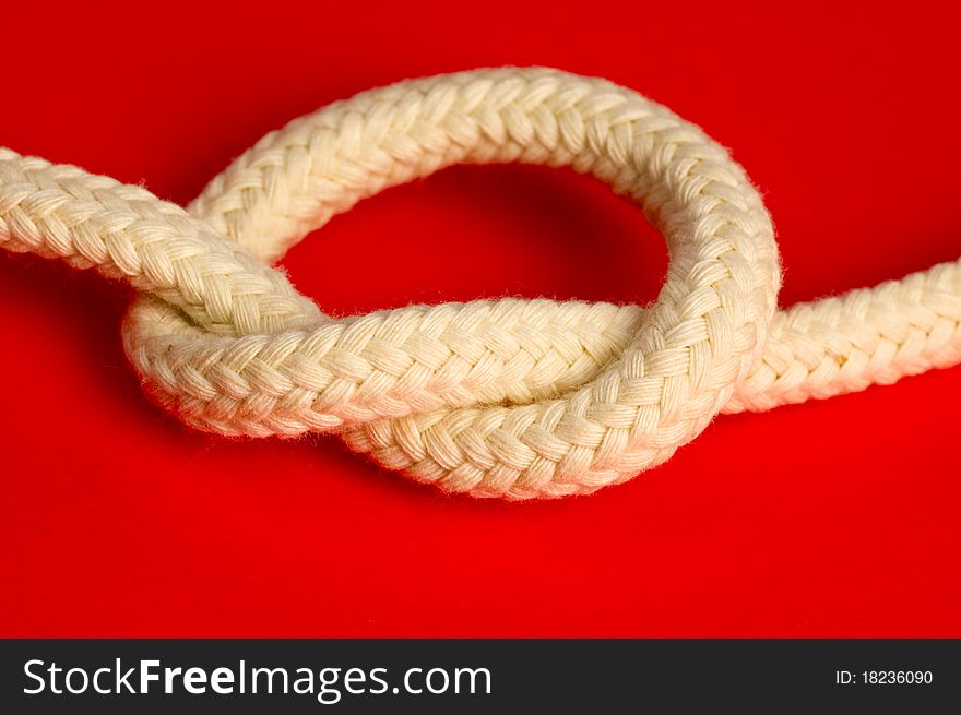 Knot of white rope on red background