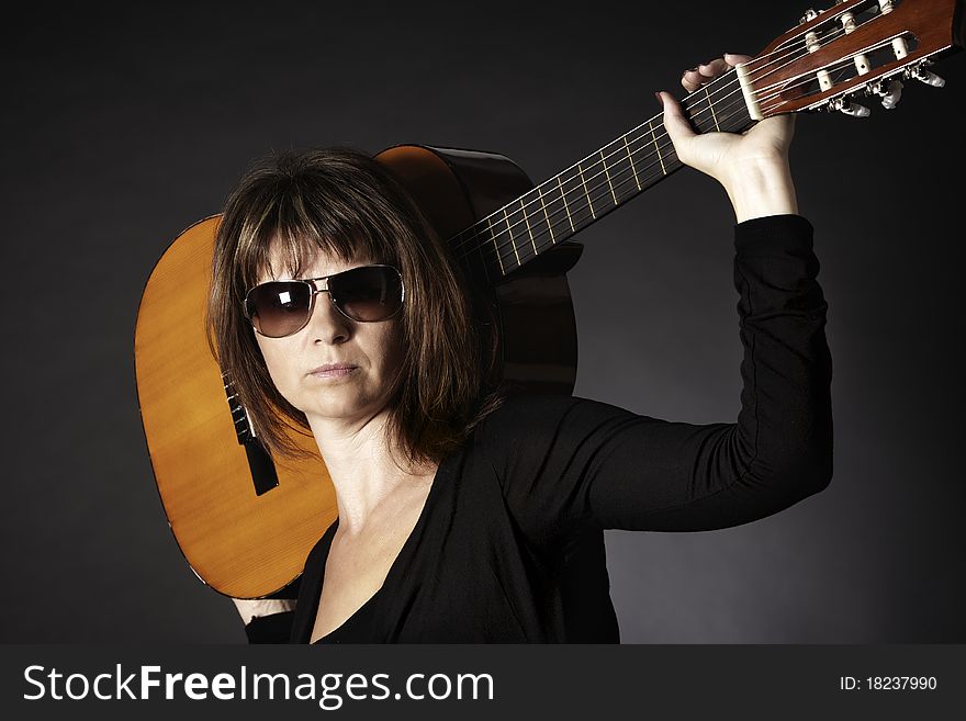 Portrait of cool young woman in black posing with guitar on shoulders, isolated on black background. Portrait of cool young woman in black posing with guitar on shoulders, isolated on black background.