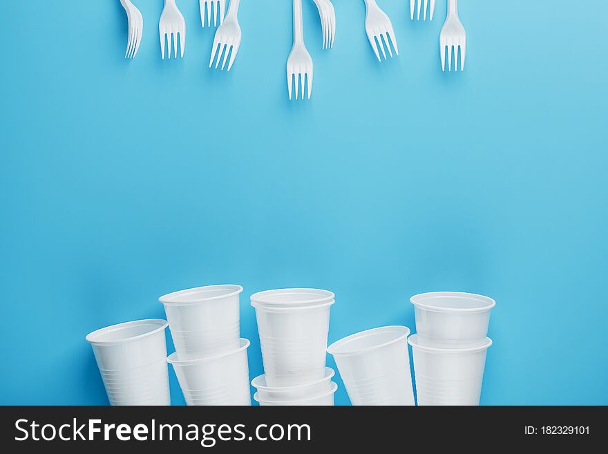 Dishes made of white plastic on a blue background. Free space. The view from the top