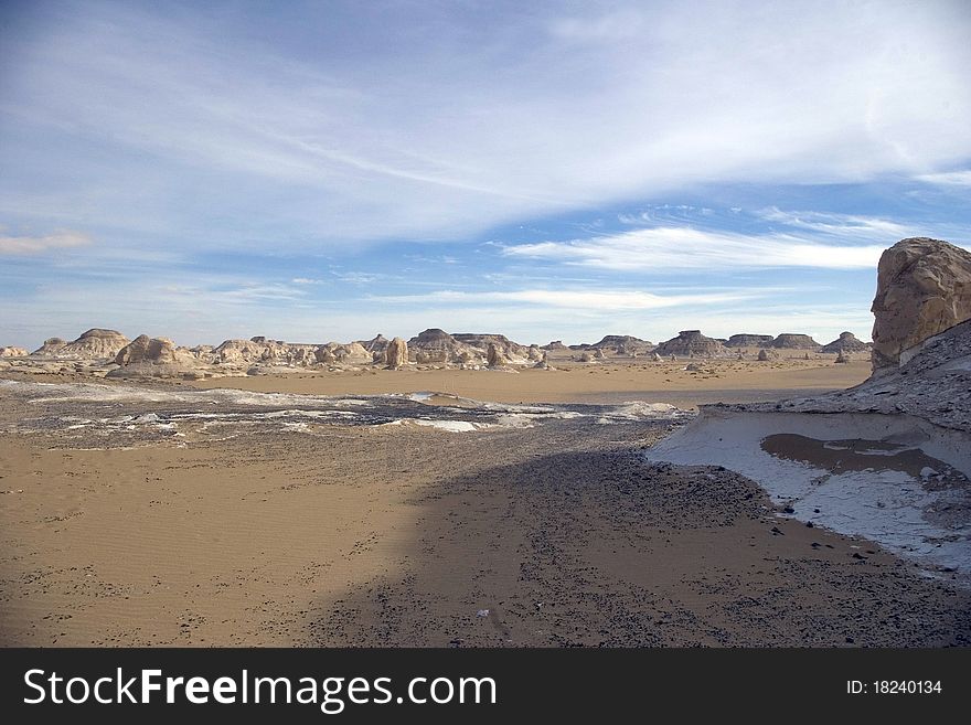 White desert landscape with rocksand white sand.