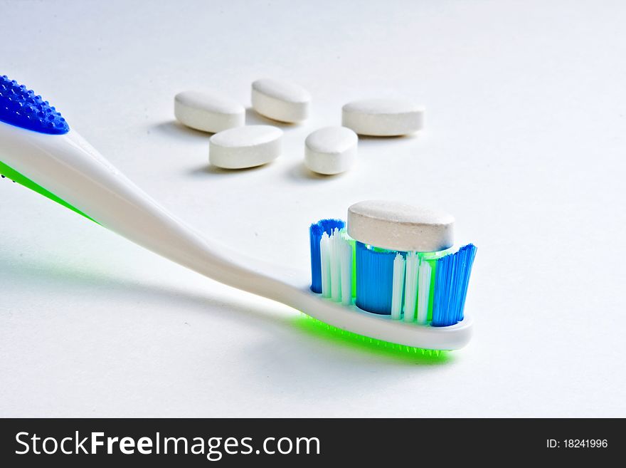 Calcium tablet resting on toothbrush bristles with other tablets in background. Calcium tablet resting on toothbrush bristles with other tablets in background