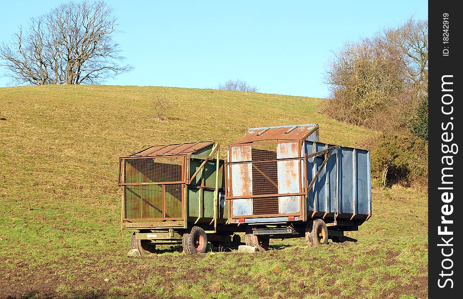 Two rusty abandoned farm trailers in field. Two rusty abandoned farm trailers in field