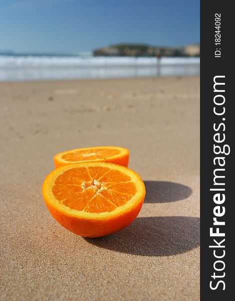 Cut orange on sand on beach