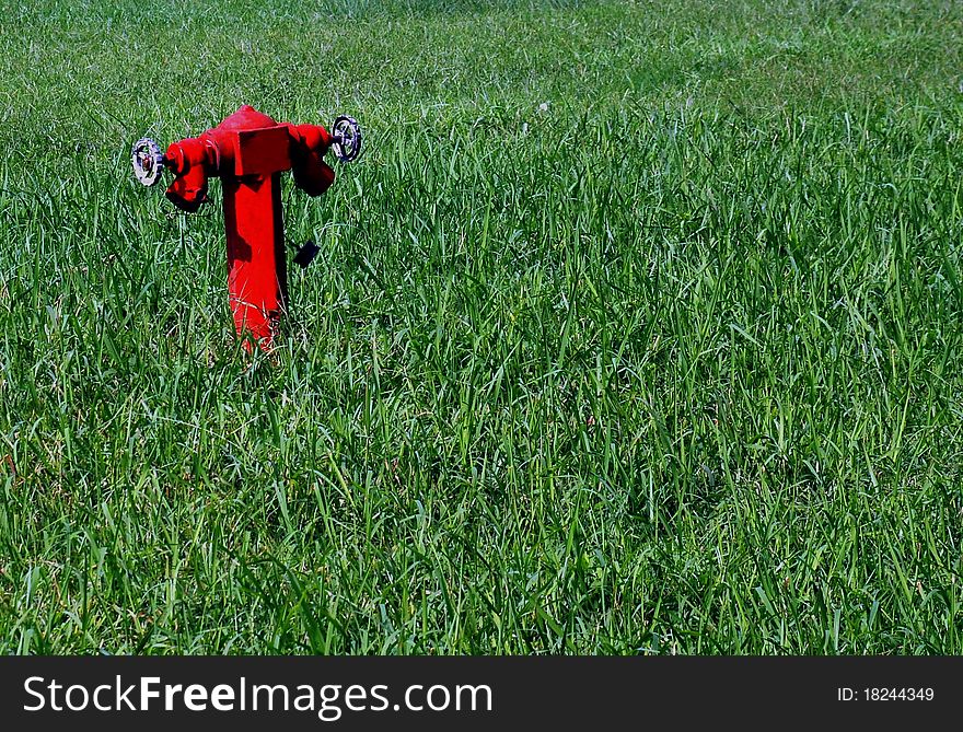 A single fireplug at a wide green lawn. A single fireplug at a wide green lawn