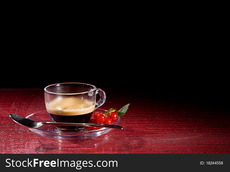 Photo of espresso coffee with currants on red glasstable
