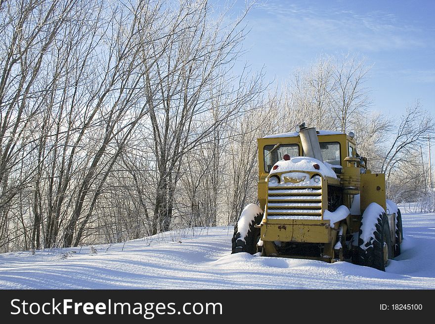 Tractor covered with snow sits idle. Tractor covered with snow sits idle