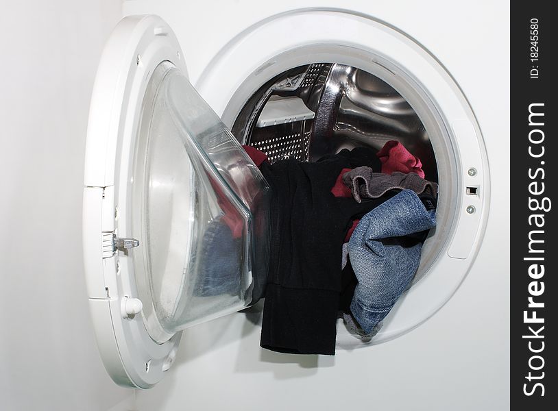 Laundry hanging out of the door of a washing machine. Laundry hanging out of the door of a washing machine