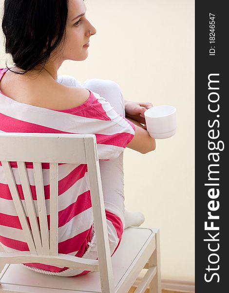 Caucasian young woman sitting on the chair and drinking tea