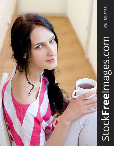 Caucasian young woman with cup of tea on the chair