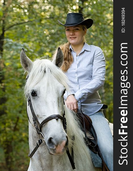 Young horsewoman sits on a white horse