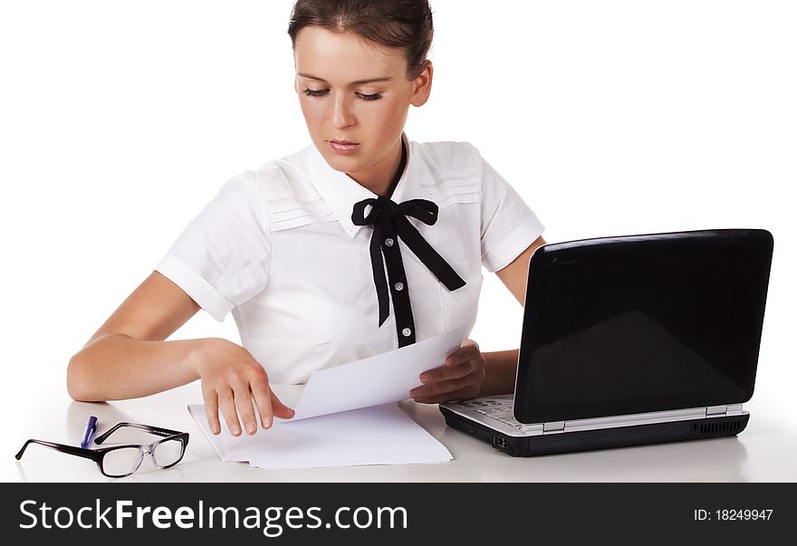 Young woman wearing glasses sitting behind a desk and a laptop computer goes through the documents. A series of modern, airy office. Young woman wearing glasses sitting behind a desk and a laptop computer goes through the documents. A series of modern, airy office.