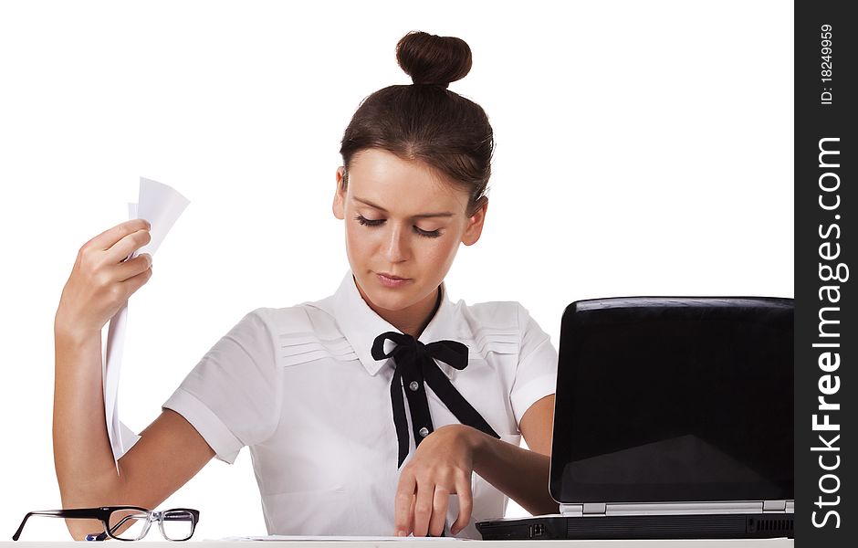 Young woman wearing glasses sitting behind a desk and a laptop computer goes through the documents. A series of modern, airy office. Young woman wearing glasses sitting behind a desk and a laptop computer goes through the documents. A series of modern, airy office.