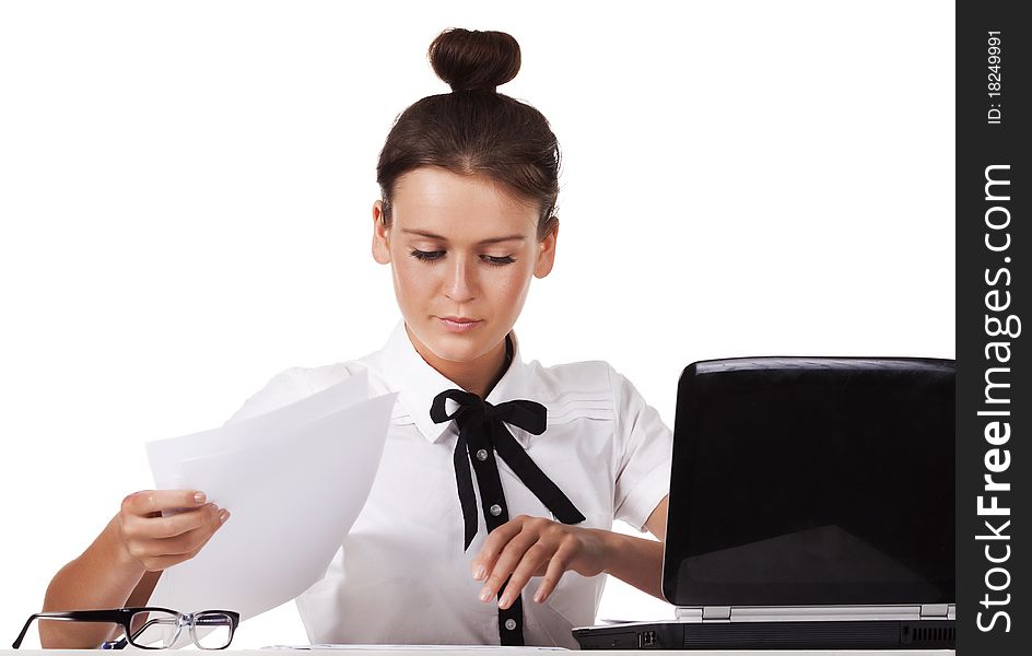 Young woman wearing glasses sitting behind a desk and a laptop computer goes through the documents. A series of modern, airy office. Young woman wearing glasses sitting behind a desk and a laptop computer goes through the documents. A series of modern, airy office.