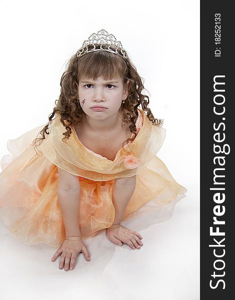 The girl the princess in a orange dress sits opposite to a white background. The girl the princess in a orange dress sits opposite to a white background