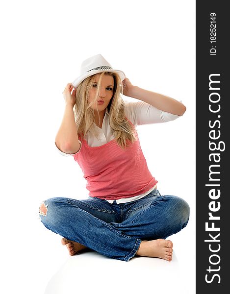 Young casual smiling woman in white hat sitting on the floor having fun isolated