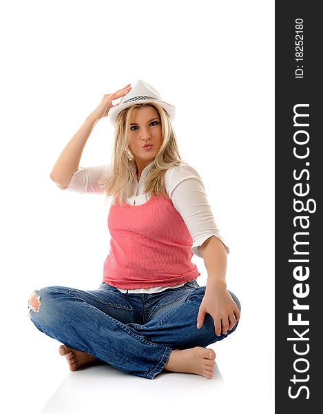 Young casual smiling woman in white hat sitting on the floor having fun isolated