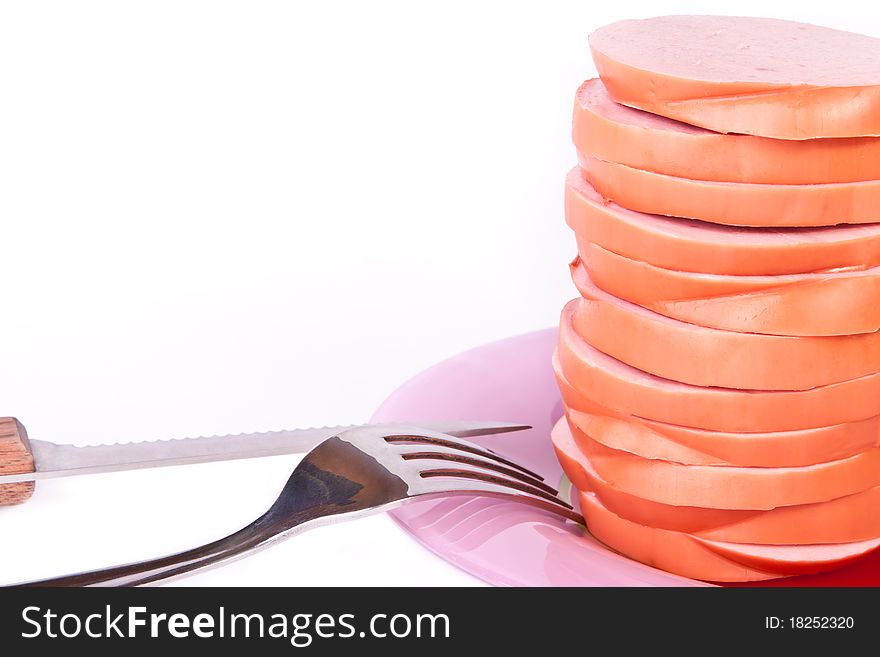 Cooked sausage on the plate with knife and fork across white. Cooked sausage on the plate with knife and fork across white