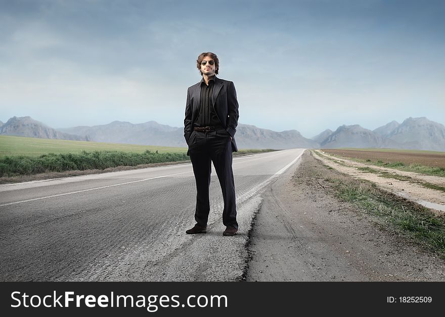 Young elegant man standing on a countryside road. Young elegant man standing on a countryside road